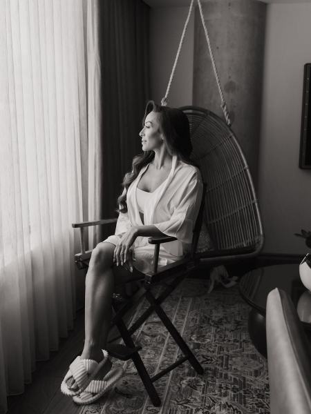 Bride sitting in white robe while sipping champagne at The Ben Autograph Collection Hotel Palm Beach