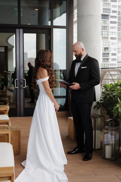 Bride and groom holding hands while exchanging vows at The Ben Autograph Collection Hotel Palm Beach