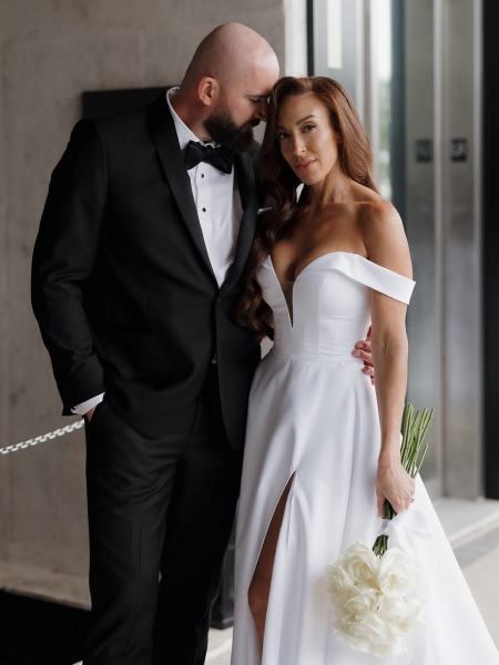 Wide shot of couple standing near hotel entrance under natural light at The Ben Autograph Collection Hotel Palm Beach
