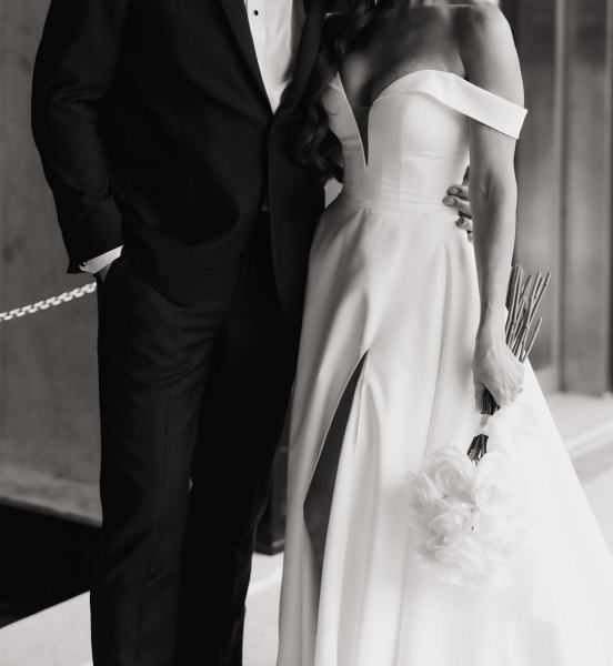 Wide shot of couple standing near hotel entrance under natural light at The Ben Autograph Collection Hotel Palm Beach