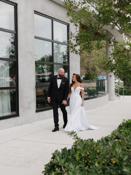 Wide-angle shot of couple walking with hotel architecture in the background at The Ben Autograph Collection Hotel Palm Beach