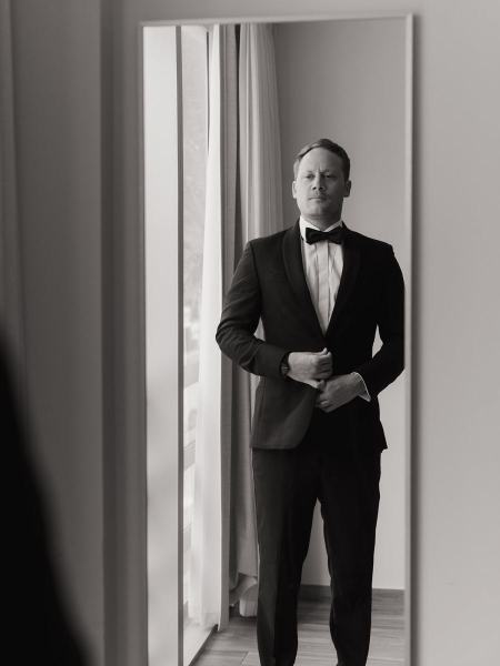 Groom looking in mirror while fixing hair and tie at Spanish Monastery Miami