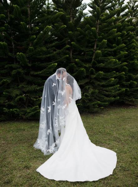 Groom kissing bride’s forehead under veil at Cinco Farms Miami