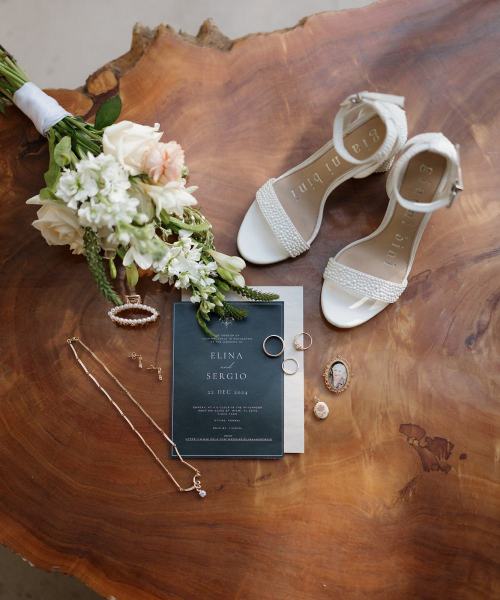 Flat lay of invitation and floral details on wood table at Cinco Farms Miami