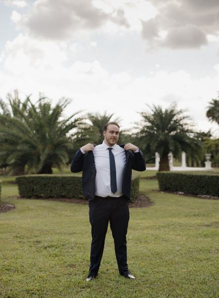 Groom putting on suit jacket at Cinco Farms Miami