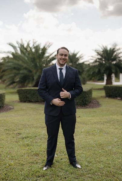 Groom putting on suit jacket at Cinco Farms Miami