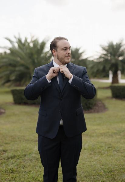 Groom putting on suit jacket at Cinco Farms Miami