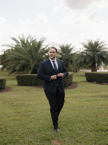 Groom putting on suit jacket at Cinco Farms Miami